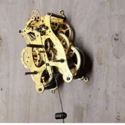 Side-angle view of a Seth Thomas lyre-style spring-driven clock movement showing gear trains and wear during restoration inspection.