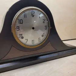 Front view of antique Gilbert mantel clock case showing original dial, bezel, and wooden housing.